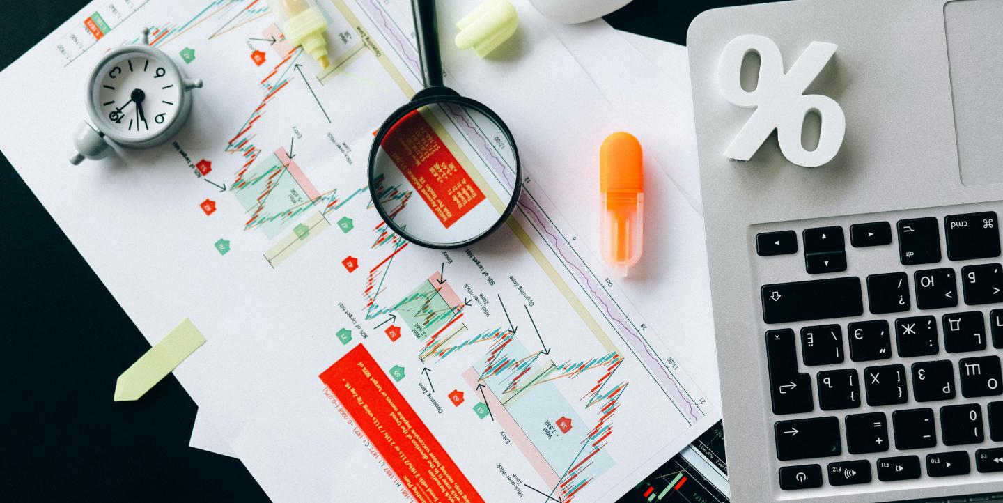 A macbook, with graphs, highlighters, a magnifying glass and more