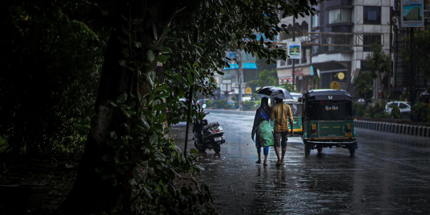 A couple waking down the street with an umbrella.