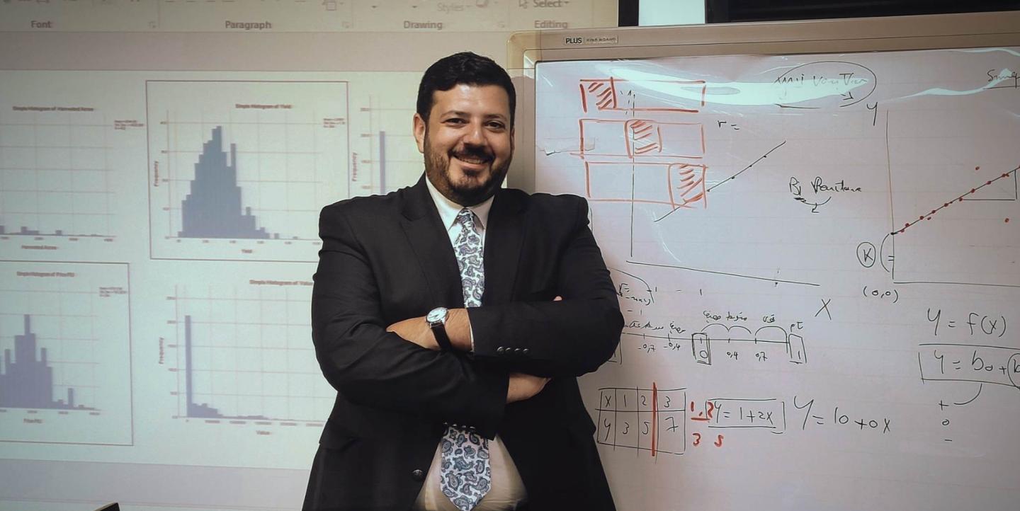 Eleraqi posing in front of a white board.