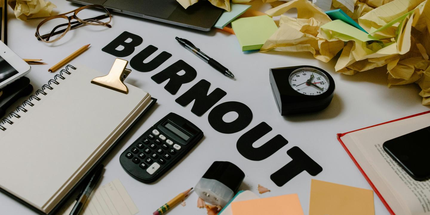Fournitures de bureau et papiers en boule sur un bureau avec le mot burnout au milieu