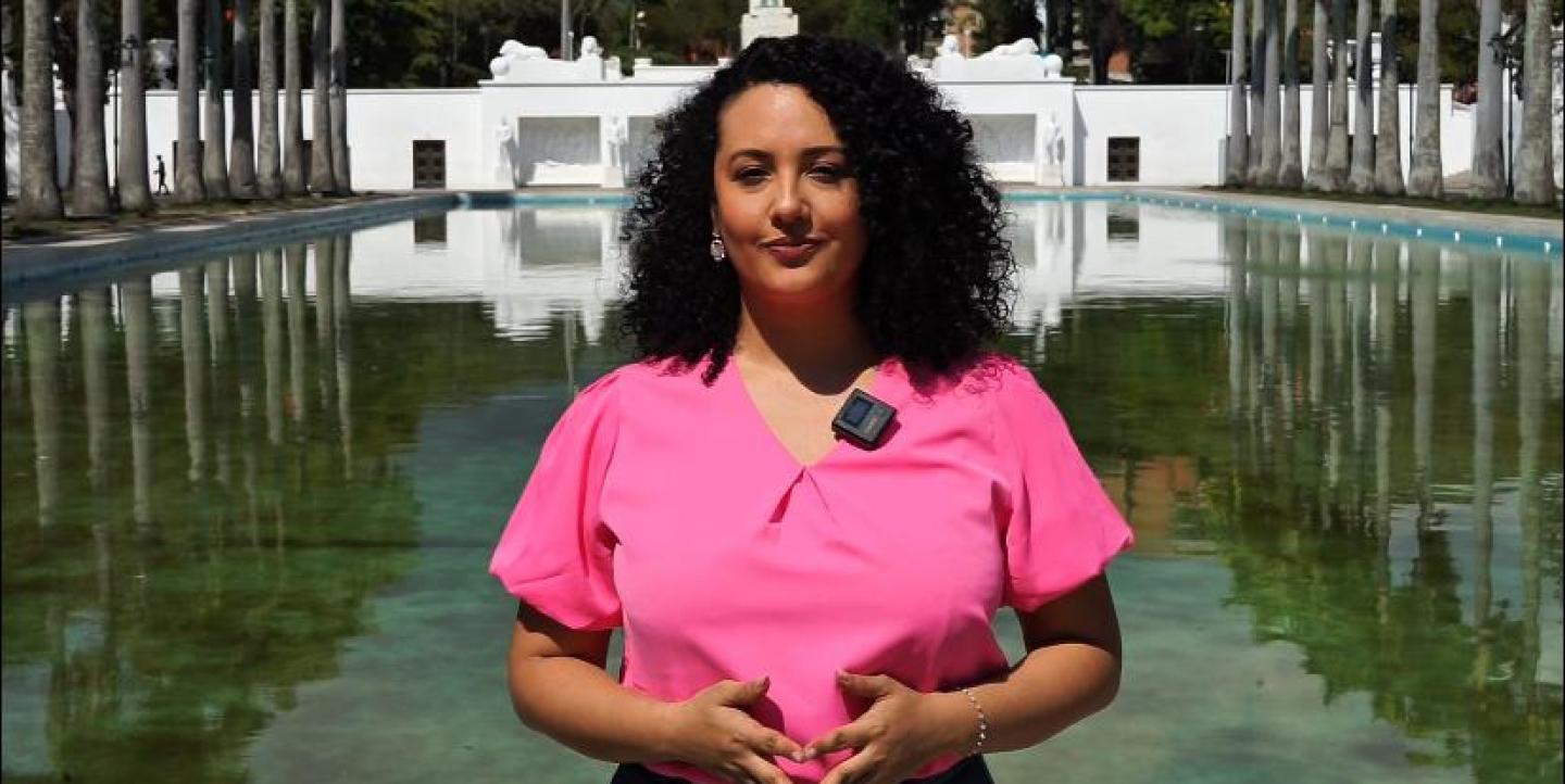 Ana standing in front of the camera wearing a pink shirt.