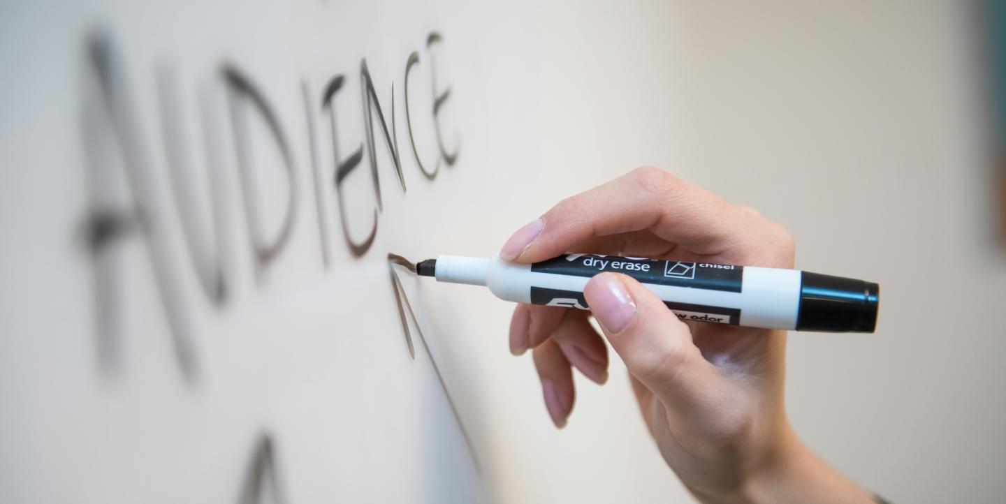 Person writing audience on a white board.