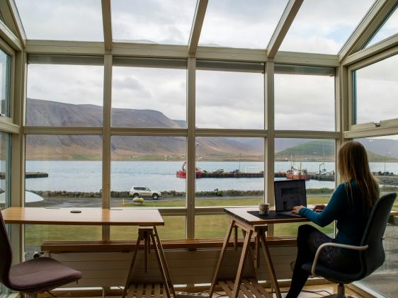  امرأة تعمل على جهاز كومبيوتر محمول أمام نافذة تُظهر الجبال