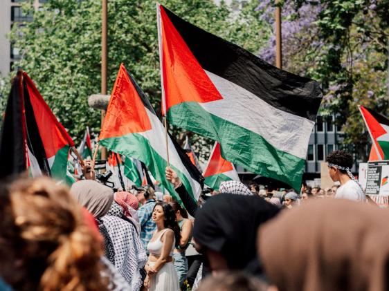 أشخاص في حشد يرفعون الأعلام الفلسطينية