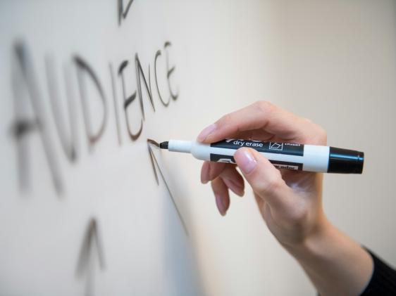 Person writing audience on a white board.