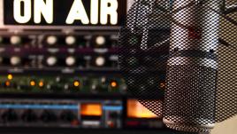 A microphone with an on air sign in the background. 