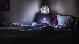 Une femme, seule, sur son ordinateur, dans la nuit 