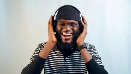 Un homme africain souriant écoute du son avec un casque audio