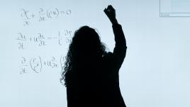 Une personne écrit des équations sur un tableau blanc