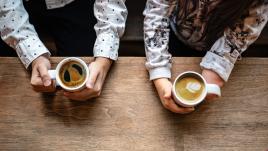 Two people holding coffee cups, one with an amputated hand