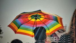 Hombre con paraguas arco iris en una protesta