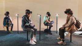 Four people sitting in a room with VR headsets on