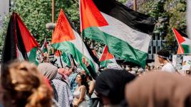 People in a crowd flying Palestinian flags