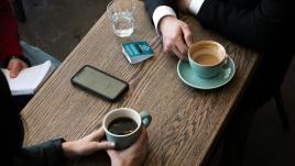 a couple of people sitting at a table with a cup of coffee