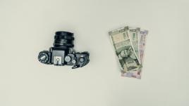 Un appareil photo à côté de quelques rupees sur un fond blanc