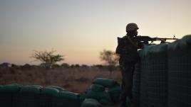 Soldier looking over a barricade at sunset