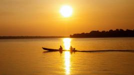 Deux hommes sur un bateau au crépuscule en Amazonie