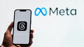 Meta logo on a phone in front of a white background that says "Meta"