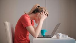 Woman with her head in her hands looking at a computer