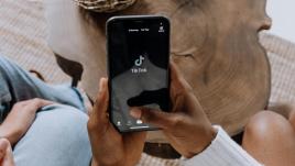 Someone holding their phone and the TikTok logo on the screen.