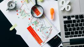 A macbook, with graphs, highlighters, a magnifying glass and more