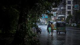 A couple waking down the street with an umbrella.