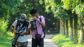 Two men looking at their cameras while in nature.