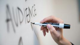 Person writing audience on a white board.